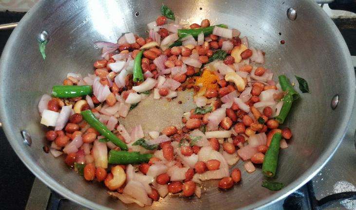 Take a pan and add in oil, mustard, chana, urad dal, peanuts, onion, green chili, turmeric powder, curry leaves.