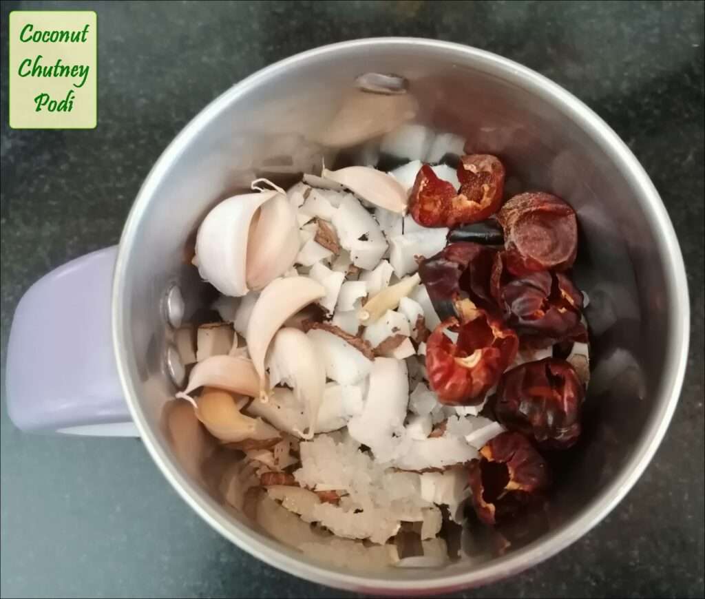 Take a mixer jar and add in chopped dry coconuts, red chilies, kashmiri chili, garlic pods and salt to taste.