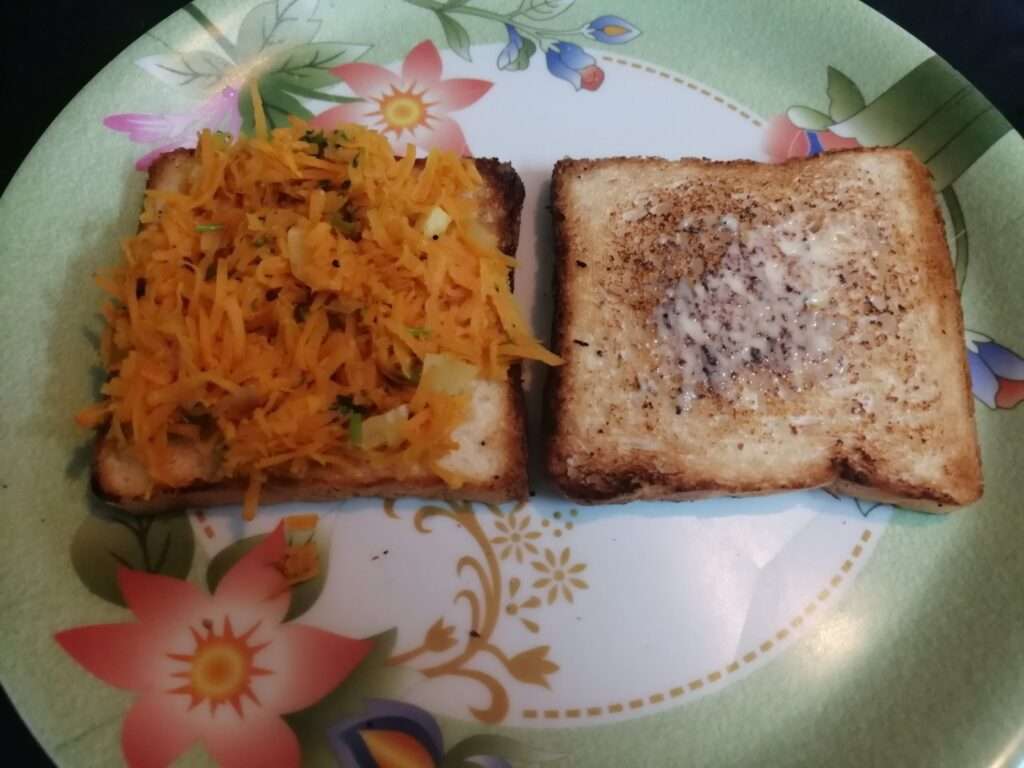 Take a serving plate and place the toasted bread and spread some butter, add prepared carrot stuffing.